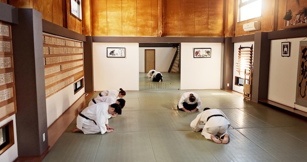 Zdjęcie grupa klasy aikido i studenci sztuk walki kłaniają się i szanują z spokojem na treningu w siłowni dojo japończycy czarny pas i klub do ćwiczeń treningu lub fitness z walką konflikt lub bitwę