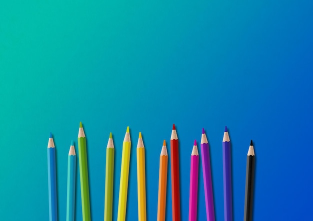 Grupa kolorowych ołówków wyizolowanych na niebiesko Poziome tło