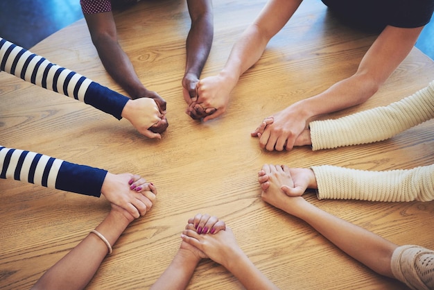 Grupa kręgów i trzymanie się za ręce z ludźmi modlą się i wspierają wiarę, zaufanie lub solidarność na biurku Praca zespołowa pomocna dłoń i razem z modlitwą religijną lub wdzięcznością z uważnością na stole