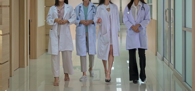Grupa lekarek spacerujących i omawiających diagnozę w korytarzu szpitalnym Koncepcja pracy zespołowej