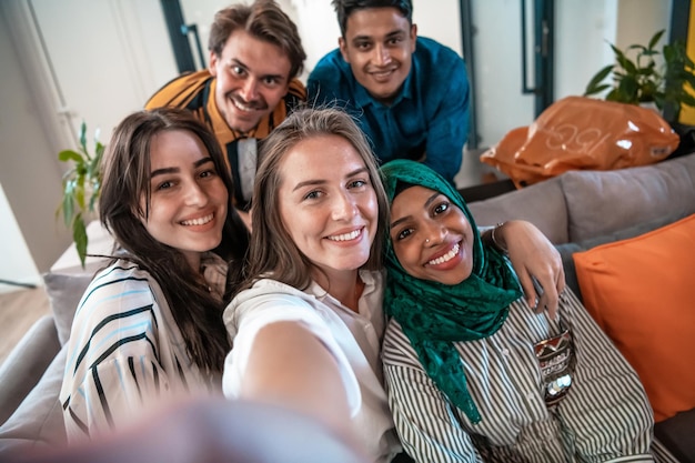 Grupa ludzi biznesu podczas przerwy w pracy robienia zdjęć selfie, ciesząc się wolnym czasem w strefie relaksu w nowoczesnym biurze startowym na otwartym planie. Selektywne skupienie. Zdjęcie wysokiej jakości