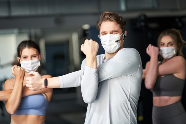 grupa ludzi ćwiczących na siłowni w maskach z powodu covid-19