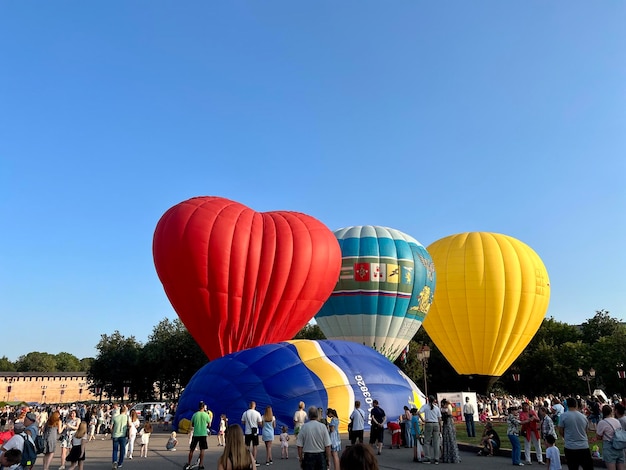 Zdjęcie grupa ludzi gromadzi się wokół balonu z czerwonym sercem na dole.