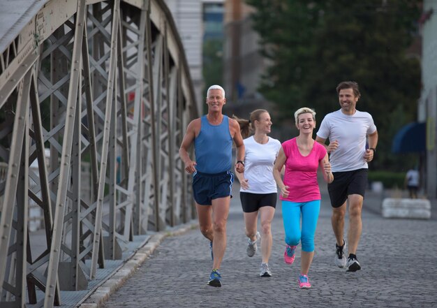 grupa ludzi jogging zespół biegaczy na porannym treningu ze wschodem słońca w tle