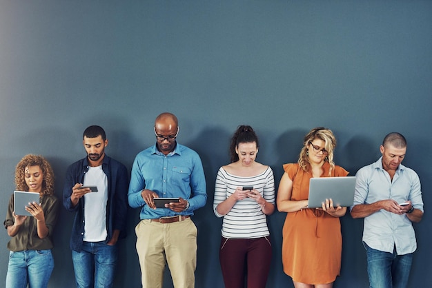 Grupa ludzi rozproszona nadużywaniem technologii na szarym tle studyjnym Wielu pracowników jest uzależnionych i ma obsesję na punkcie mediów społecznościowych z uzależnieniem od gadżetów lub urządzeń