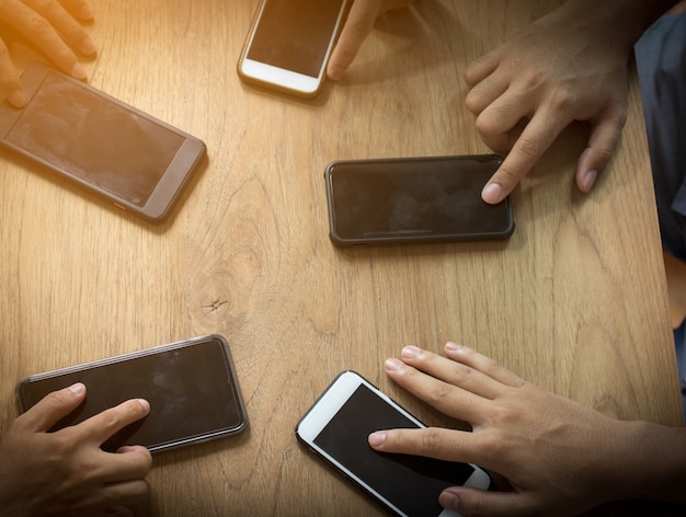 grupa ludzi używa telefonu na drewnianym stole do łączenia się i komunikacji