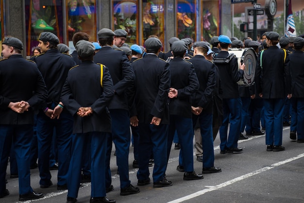 Grupa ludzi w niebieskich mundurach stoi w kolejce przed budynkiem z napisem „słowo” z przodu. "
