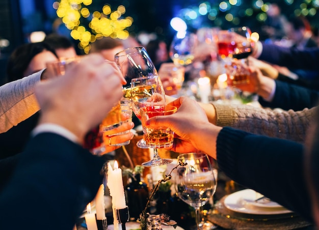 Grupa ludzi w okularach wznosi toast świętuje święta Bożego Narodzenia na tle kolorowych girland