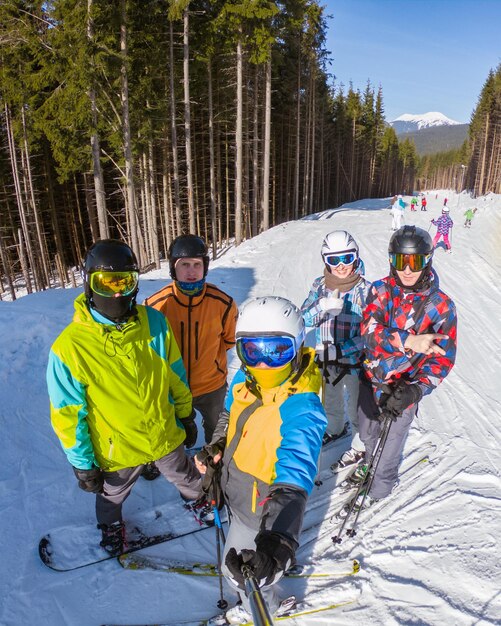 Zdjęcie grupa ludzi z snowboardami i nartami robiąca selfie na szczycie wzgórza w słoneczny dzień