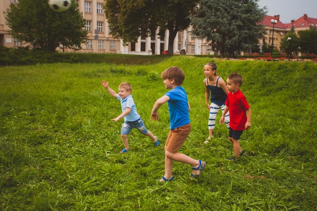 Zdjęcie grupa małych dzieci próbujących złapać piłkę nożną koncepcja aktywnego wypoczynku