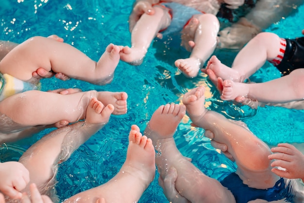 Grupa matek z małymi dziećmi w klasie pływania dla dzieci z trenerem.