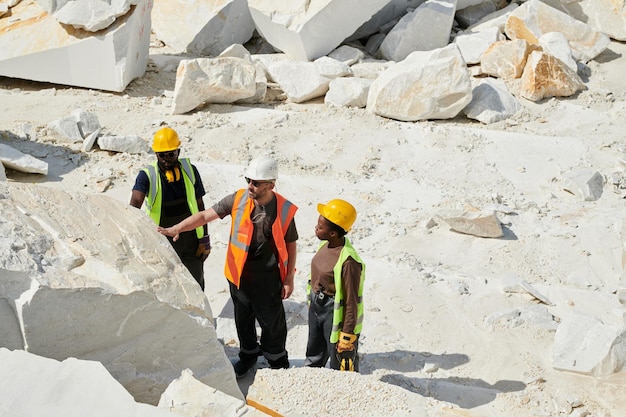 Grupa międzykulturowych pracowników kamieniołomu sprawdzająca jakość skał marmurowych