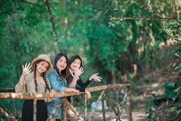 Grupa młodych azjatyckich kobiet stojących na bambusowym moście patrzy na piękną przyrodę podczas wspólnego biwakowania w lesie ze szczęściem