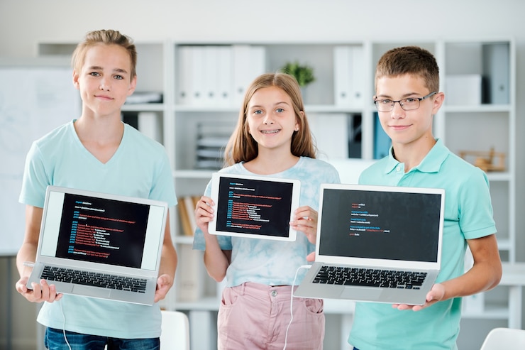 Zdjęcie grupa młodych chłopców i dziewczyn trzymających laptopy i touchpad, pokazując swoje ostatnie prace na koniec roku szkolnego