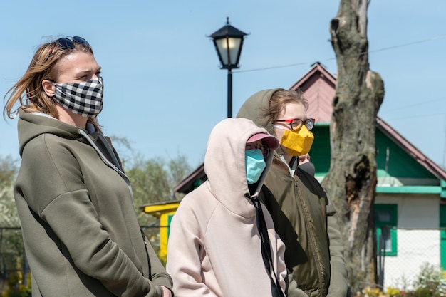 Grupa młodych dziewcząt stoi na ulicy i odwraca wzrok. Twarze dziewczynek są zakryte maseczkami chroniącymi przed zarażeniem koronawirusem Środki ochrony osobistej przeciwko Covid19 Bezpieczny wypoczynek na świeżym powietrzu