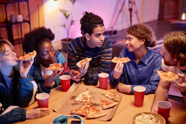 Grupa młodych ludzi jedzących pizzę na imprezie domowej