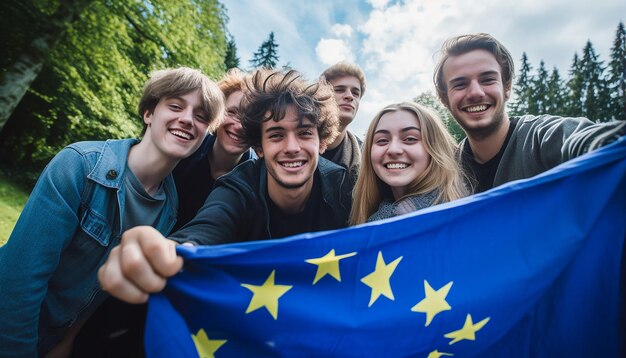 Zdjęcie grupa młodych ludzi robi sobie selfie, w tle powiewa flaga unii europejskiej