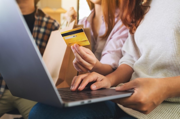 Grupa młodych ludzi używających laptopa i karty kredytowej do wspólnych zakupów online