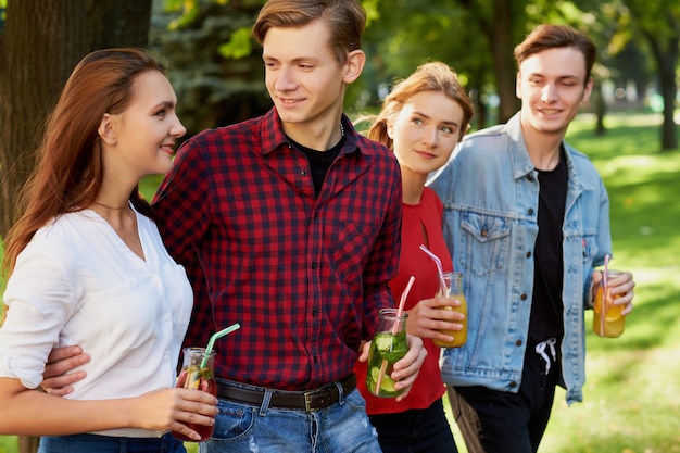 Grupa młodych ludzi z koktajlami detoksykacyjnymi spędza razem czas w lecie