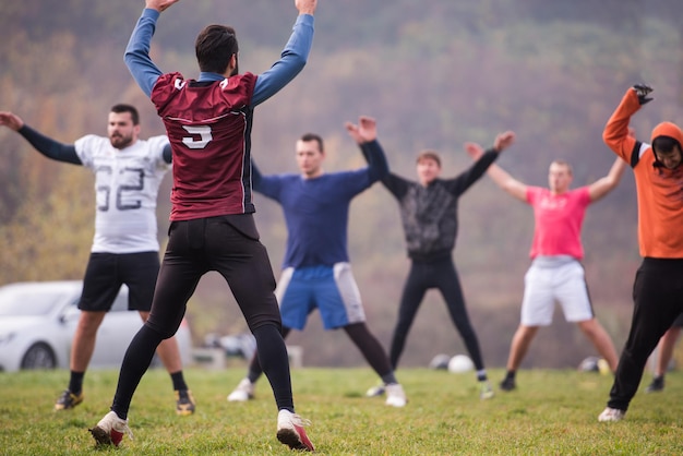 grupa młodych piłkarzy futbolu amerykańskiego rozciągająca się i wspólnie rozgrzewająca przed treningiem