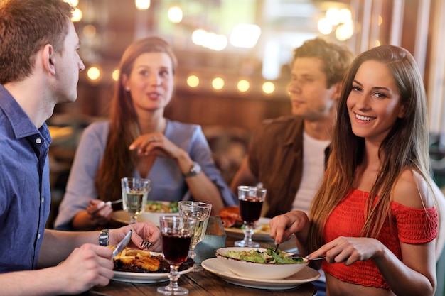 Grupa młodych przyjaciół cieszących się posiłkiem w restauracji