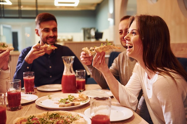 Grupa Młodych Przyjaciół, Którzy Siedzą Razem W Domu I Jedzą Pizzę