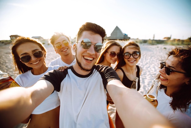 Grupa młodych przyjaciół robiących selfie i bawiących się na plaży wakacje letnie odpoczynek