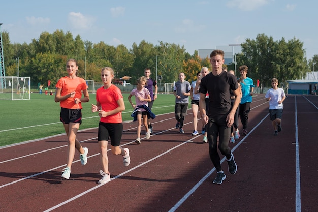 Grupa młodych sportowców trenujących na stadionie szkolne treningi gimnastyczne lub lekkoatletyczne