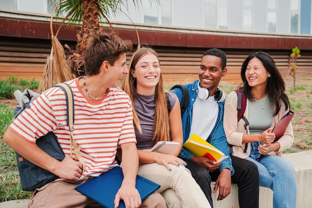 Zdjęcie grupa młodych studentów akademickich rozmawiających razem siedzących na kampusie uniwersyteckim