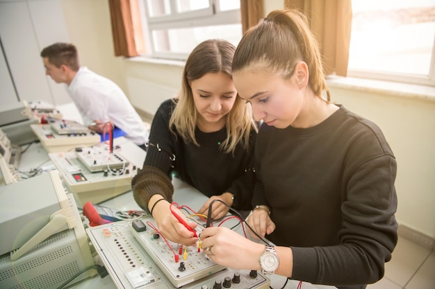 Grupa młodych uczniów odbywających praktykę zawodową techniczną z nauczycielem w klasie elektronicznej, koncepcja edukacji i technologii