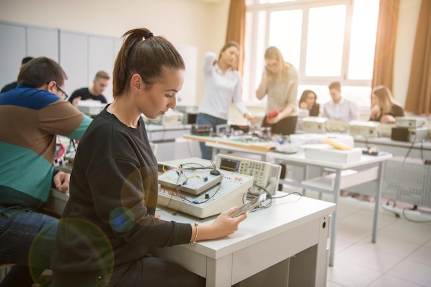 Grupa młodych uczniów odbywających praktykę zawodową techniczną z nauczycielem w klasie elektronicznej, koncepcja edukacji i technologii