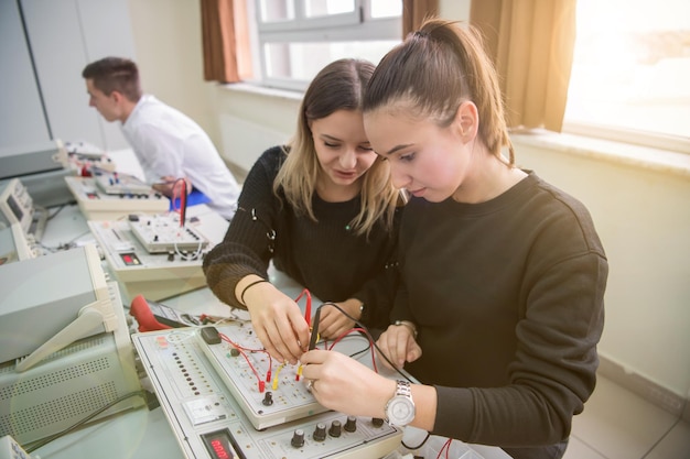 Grupa młodych uczniów odbywających praktykę zawodową techniczną z nauczycielem w klasie elektronicznej, koncepcja edukacji i technologii