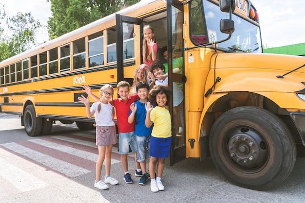 Grupa młodych uczniów uczęszczających do szkoły podstawowej w żółtym autobusie szkolnym - Dzieci ze szkoły podstawowej bawią się