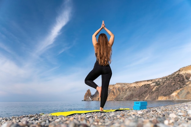 Grupa młodych womans instruktor fitness w sportowej legginsy i topy rozciągające się na siłowni przed pilates na macie do jogi w pobliżu dużego okna w słoneczny dzień kobiece fitness joga koncepcja rutyny