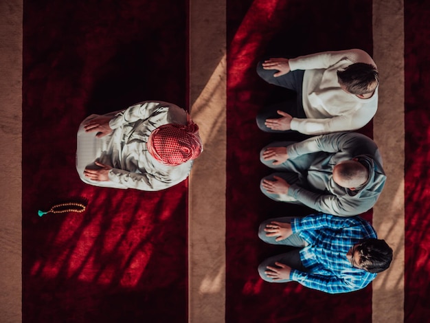 Grupa muzułmanów w nowoczesnym meczecie modlącym się muzułmańskim namazem modlitewnym podczas świętego miesiąca Ramadanu.