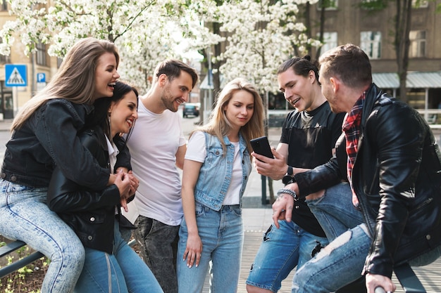 Grupa najlepszych przyjaciół bawi się na ulicy. Młodzi ludzie chętnie widzą się podczas spotkania.