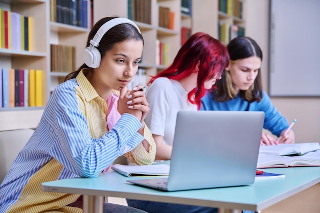 Grupa nastoletnich studentów studiuje w bibliotece szkolnej