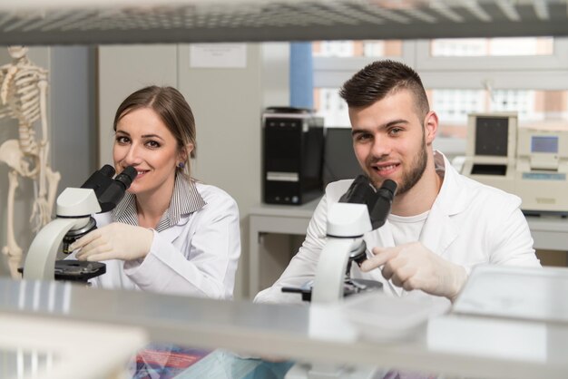 Grupa naukowców prowadzących badania w środowisku laboratoryjnym patrząca w mikroskop