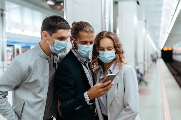 Grupa pasażerów w maskach ochronnych robi selfie w metrze