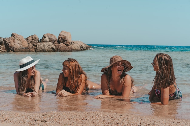 Grupa pięknych młodych kobiet odpoczywa na plaży.