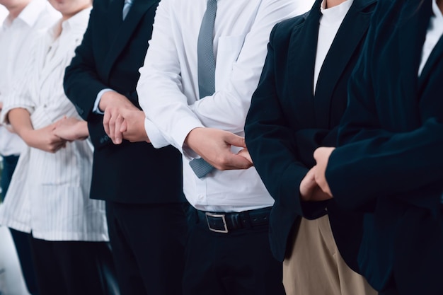 Grupa pracowników biurowych trzymających się za rękę w kolejce w celu promowania harmonii w miejscu pracy