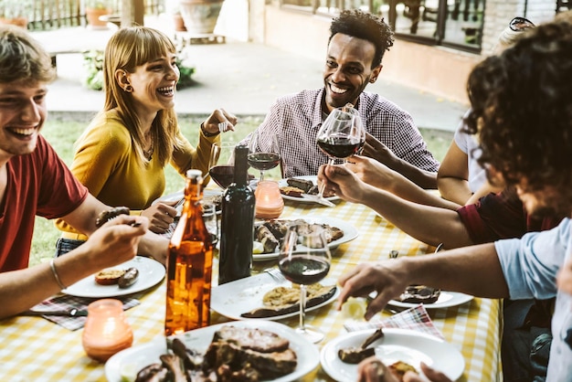 Grupa przyjaciół bawi się przy kolacji z grilla na świeżym powietrzu w restauracji ogrodowej?