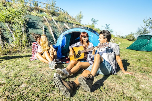 Grupa przyjaciół bawiąca się na świeżym powietrzu na obozie piknikowym z zabytkową gitarą