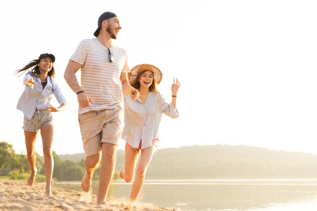 Grupa przyjaciół bawiących się biegając po plaży - koncepcja młodzieży, letniego stylu życia i wakacji