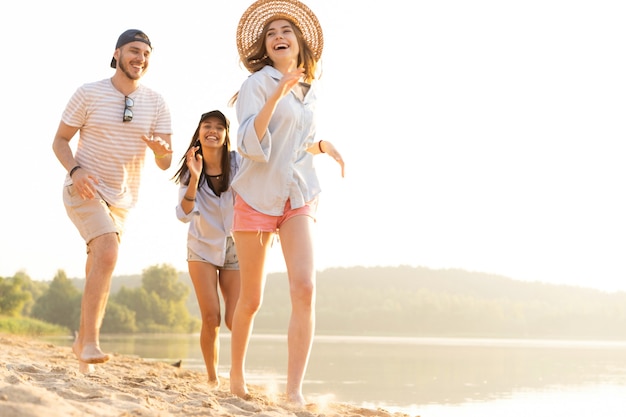 Grupa przyjaciół bawiących się biegając po plaży - koncepcja młodzieży, letniego stylu życia i wakacji