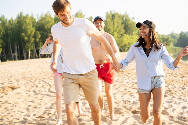 Grupa przyjaciół bawiących się biegając po plaży - koncepcja młodzieży, letniego stylu życia i wakacji