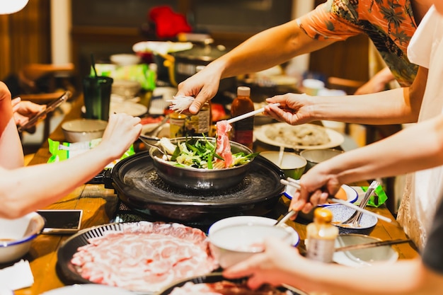 Grupa przyjaciół gotujących w domu chiński hotpot shabu