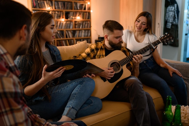 Grupa przyjaciół na imprezie domowej grająca na gitarze i ciesząca się muzyką