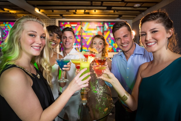Grupa przyjaciół opiekania szklankę koktajlu w barze