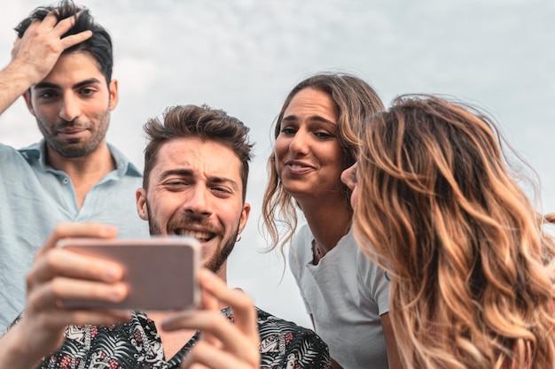 Grupa przyjaciół robi selfie, bawiąc się smartfonem